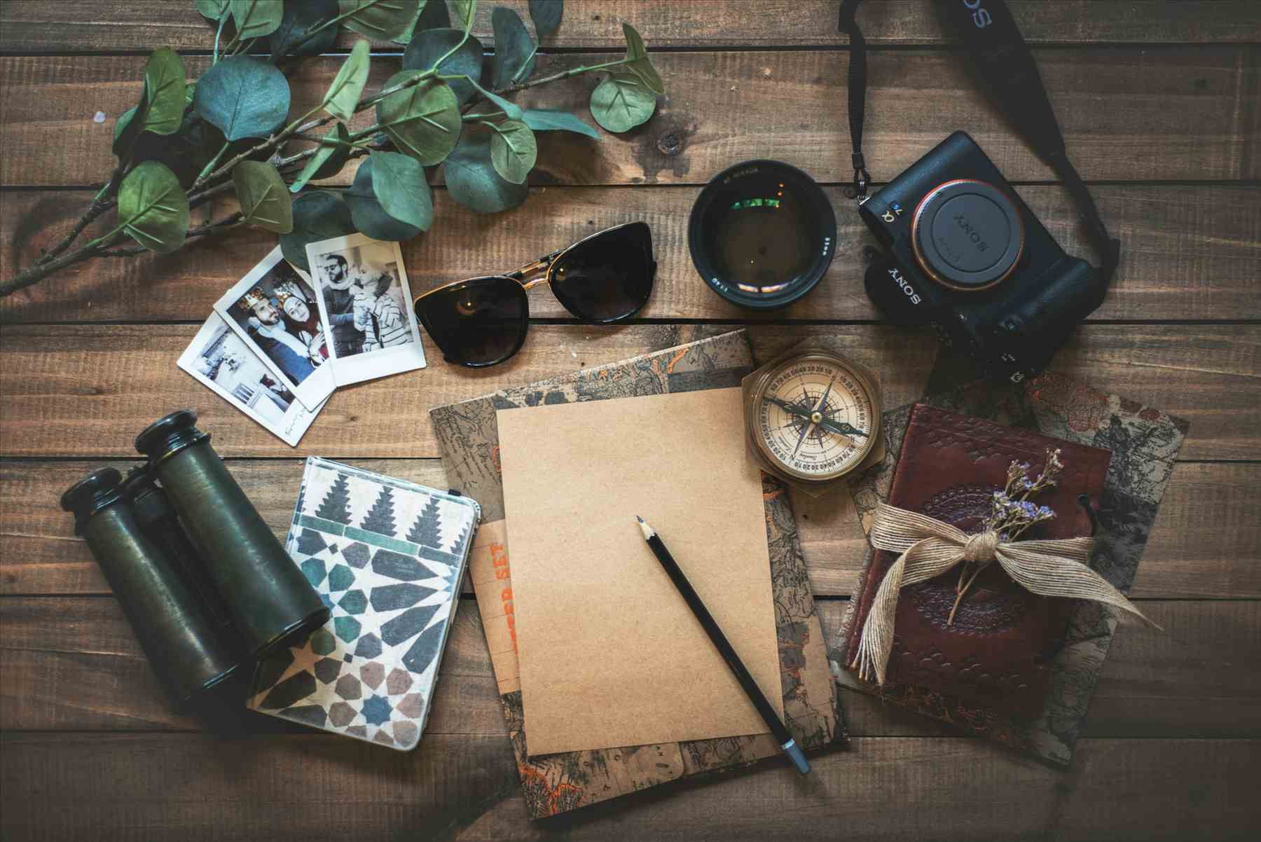Flat-lay of travel planning essentials — map, camera, sunglasses, notebook and compass — for an Arizona road trip