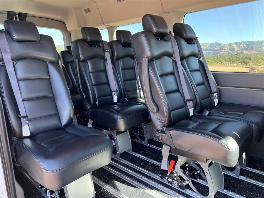 Rows of leather captain's chairs inside the 2023 Ford Transit, with Sedona red rock views through the window